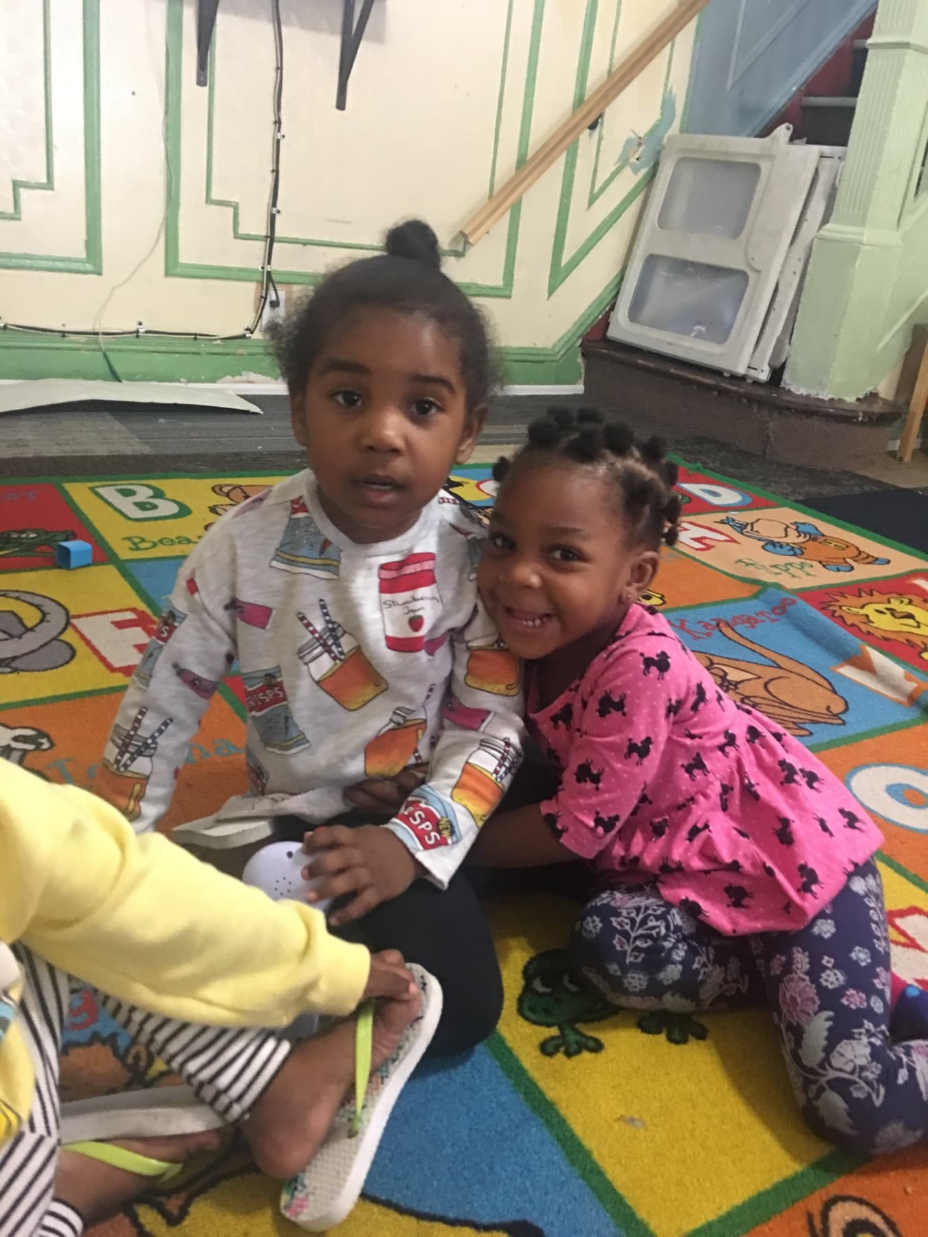 Two children sitting together on a classroom rug