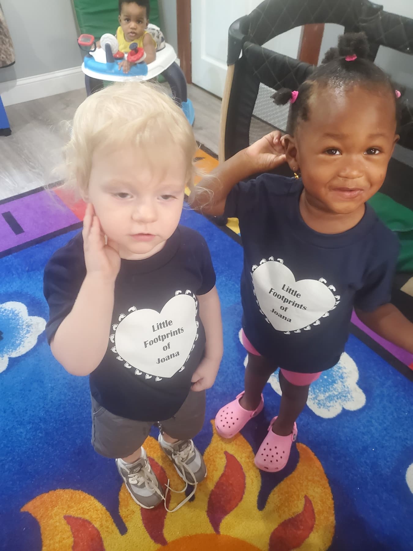 Children standing together in Little Footprints daycare shirts