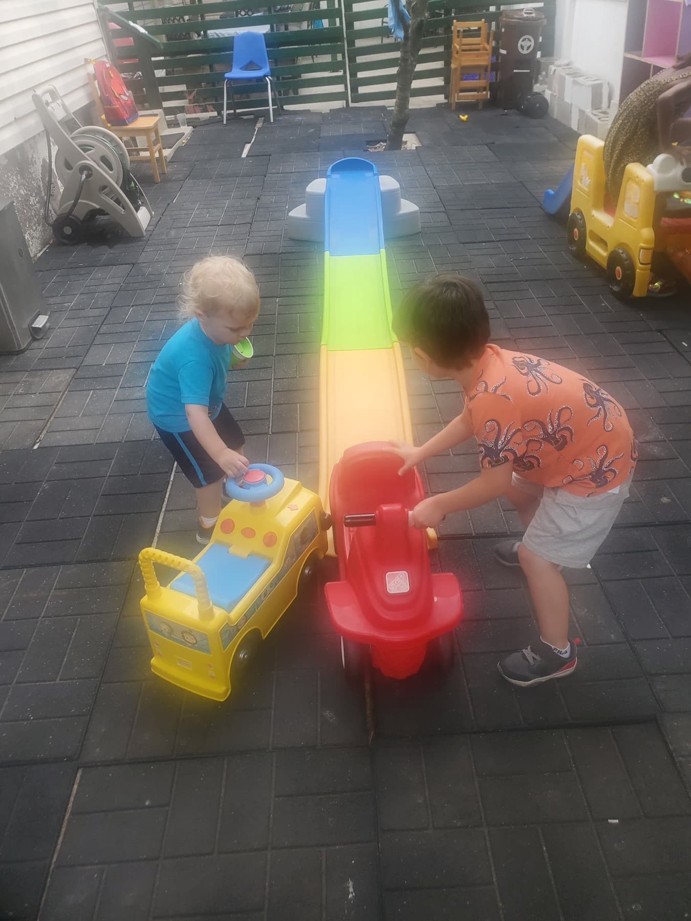 Children playing with ride-on toys in the outdoor play area