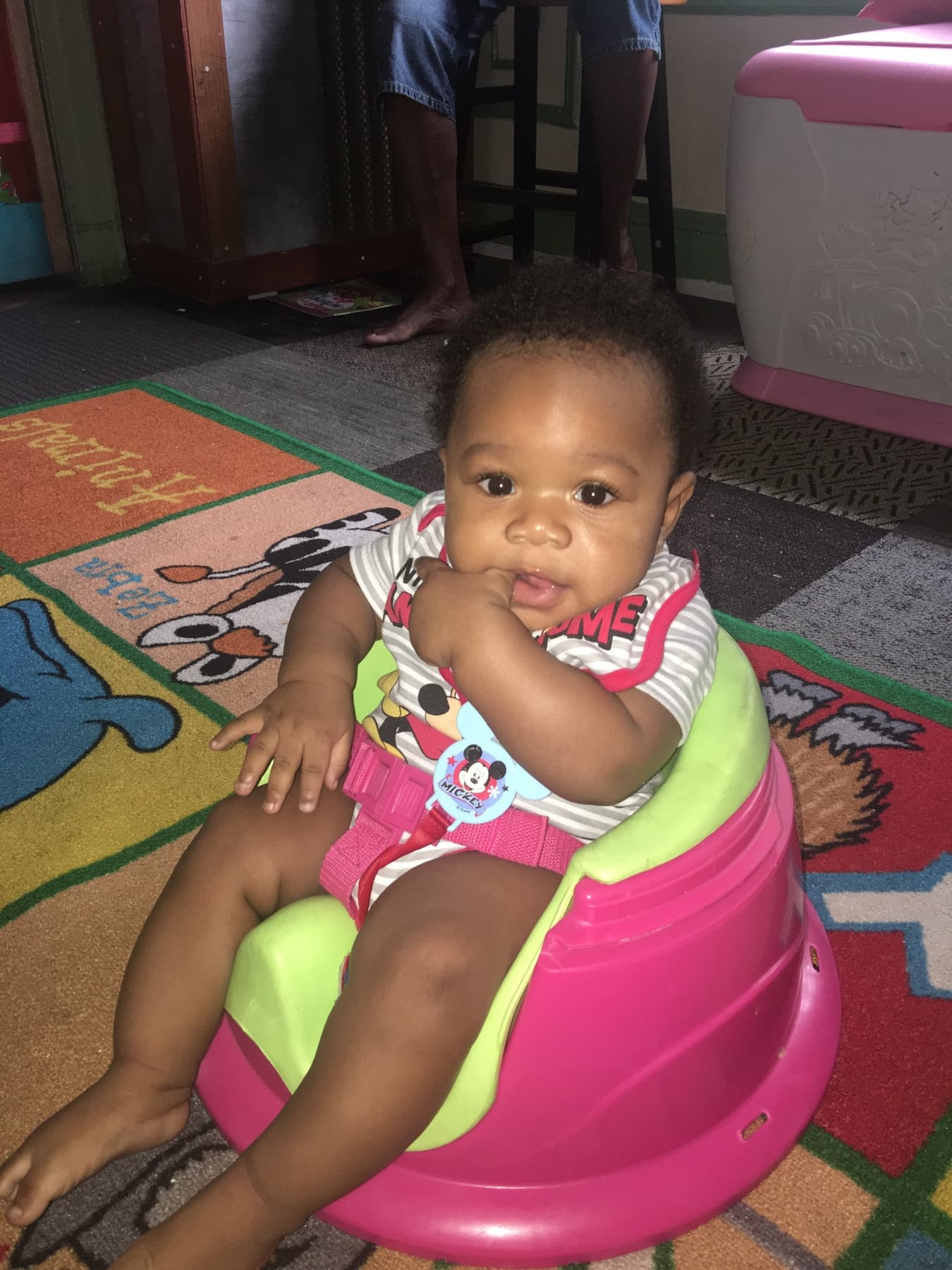 Infant seated in an activity seat on a classroom rug