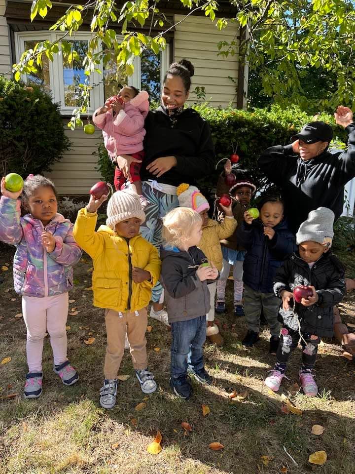 Children and caregivers outside during an apple activity