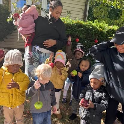 Caregivers and children holding apples outside