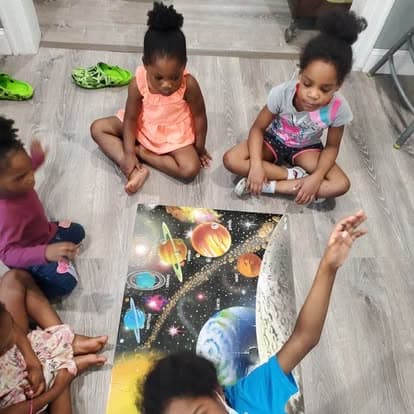 Children seated near a space-themed learning mat