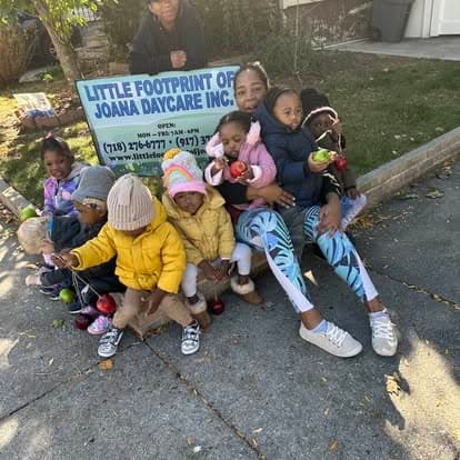 Caregiver and children gathered outside near the daycare sign